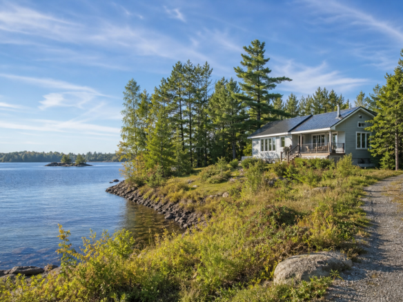Waterfront rural home near Sault Ste. Marie with lake, trees, and gravel driveway